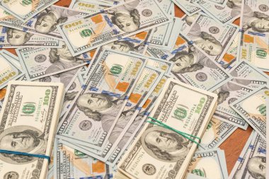 Ahşap masa arkaplan dokusunda yüzlerce dolarlık banknotlar. Bir tomar para ofis masasına saçıldı. zenginlik ve gelir kavramı