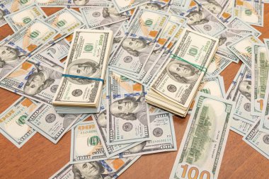 Ahşap masa arkaplan dokusunda yüzlerce dolarlık banknotlar. Bir tomar para ofis masasına saçıldı. zenginlik ve gelir kavramı