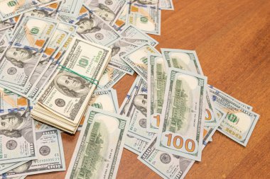 Ahşap masa arkaplan dokusunda yüzlerce dolarlık banknotlar. Bir tomar para ofis masasına saçıldı. zenginlik ve gelir kavramı
