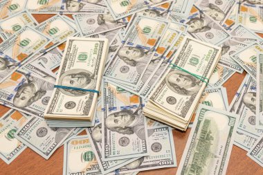 Ahşap masa arkaplan dokusunda yüzlerce dolarlık banknotlar. Bir tomar para ofis masasına saçıldı. zenginlik ve gelir kavramı