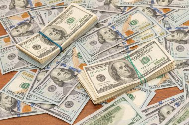 Ahşap masa arkaplan dokusunda yüzlerce dolarlık banknotlar. Bir tomar para ofis masasına saçıldı. zenginlik ve gelir kavramı