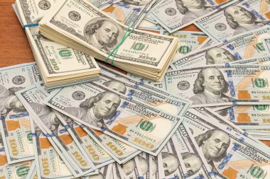 Ahşap masa arkaplan dokusunda yüzlerce dolarlık banknotlar. Bir tomar para ofis masasına saçıldı. zenginlik ve gelir kavramı