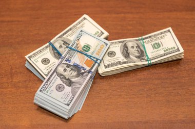 Ahşap masa arkaplan dokusunda yüzlerce dolarlık banknotlar. Bir tomar para ofis masasına saçıldı. zenginlik ve gelir kavramı