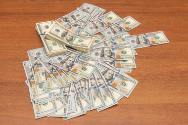 Ahşap masa arkaplan dokusunda yüzlerce dolarlık banknotlar. Bir tomar para ofis masasına saçıldı. zenginlik ve gelir kavramı