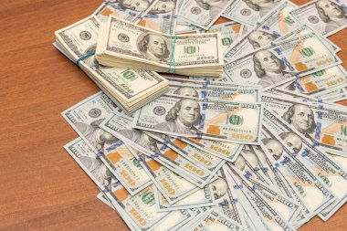 Ahşap masa arkaplan dokusunda yüzlerce dolarlık banknotlar. Bir tomar para ofis masasına saçıldı. zenginlik ve gelir kavramı
