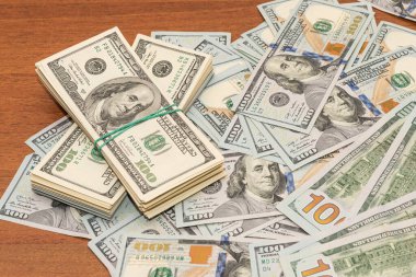 Ahşap masa arkaplan dokusunda yüzlerce dolarlık banknotlar. Bir tomar para ofis masasına saçıldı. zenginlik ve gelir kavramı