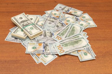 Ahşap masa arkaplan dokusunda yüzlerce dolarlık banknotlar. Bir tomar para ofis masasına saçıldı. zenginlik ve gelir kavramı