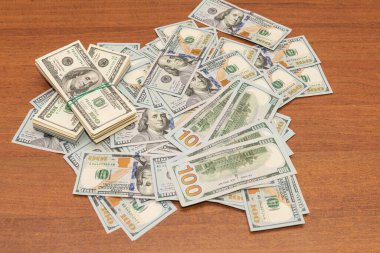 Ahşap masa arkaplan dokusunda yüzlerce dolarlık banknotlar. Bir tomar para ofis masasına saçıldı. zenginlik ve gelir kavramı