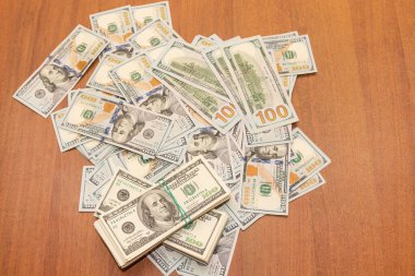 Ahşap masa arkaplan dokusunda yüzlerce dolarlık banknotlar. Bir tomar para ofis masasına saçıldı. zenginlik ve gelir kavramı