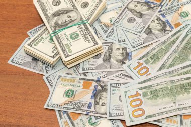 Ahşap masa arkaplan dokusunda yüzlerce dolarlık banknotlar. Bir tomar para ofis masasına saçıldı. zenginlik ve gelir kavramı