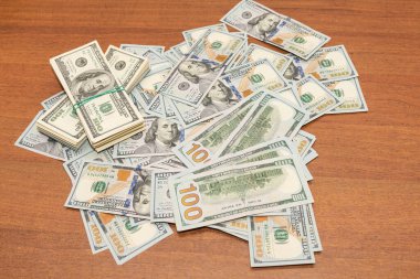 Ahşap masa arkaplan dokusunda yüzlerce dolarlık banknotlar. Bir tomar para ofis masasına saçıldı. zenginlik ve gelir kavramı