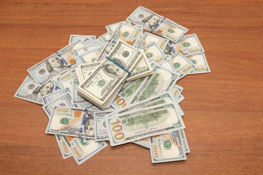 Ahşap masa arkaplan dokusunda yüzlerce dolarlık banknotlar. Bir tomar para ofis masasına saçıldı. zenginlik ve gelir kavramı