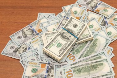 Ahşap masa arkaplan dokusunda yüzlerce dolarlık banknotlar. Bir tomar para ofis masasına saçıldı. zenginlik ve gelir kavramı