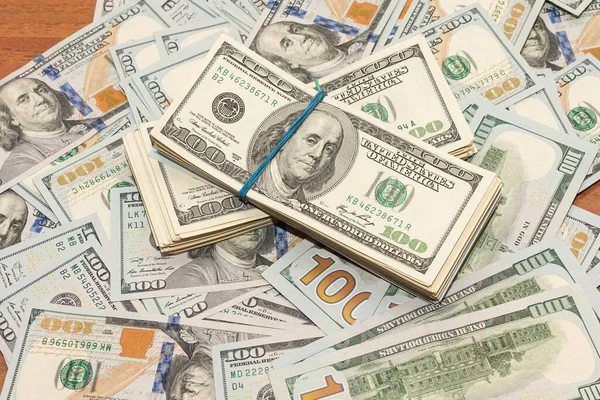 Ahşap masa arkaplan dokusunda yüzlerce dolarlık banknotlar. Bir tomar para ofis masasına saçıldı. zenginlik ve gelir kavramı