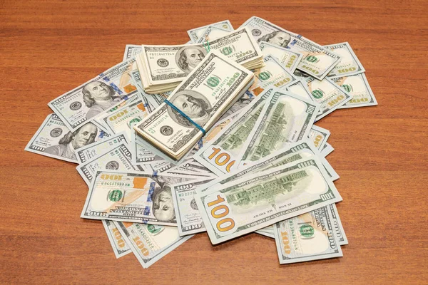 Ahşap masa arkaplan dokusunda yüzlerce dolarlık banknotlar. Bir tomar para ofis masasına saçıldı. zenginlik ve gelir kavramı