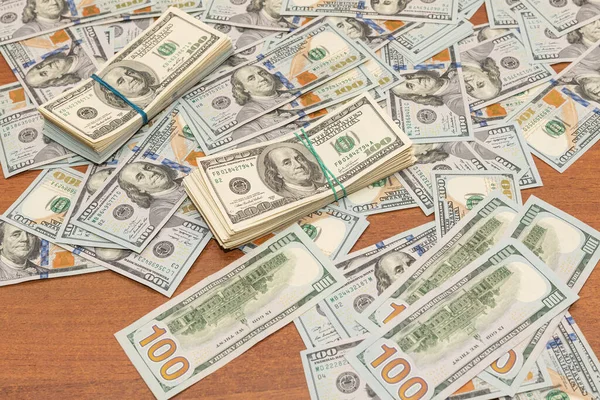 Ahşap masa arkaplan dokusunda yüzlerce dolarlık banknotlar. Bir tomar para ofis masasına saçıldı. zenginlik ve gelir kavramı