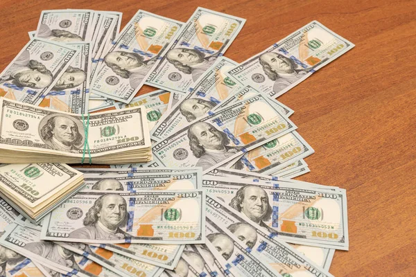 Ahşap masa arkaplan dokusunda yüzlerce dolarlık banknotlar. Bir tomar para ofis masasına saçıldı. zenginlik ve gelir kavramı