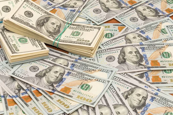 Ahşap masa arkaplan dokusunda yüzlerce dolarlık banknotlar. Bir tomar para ofis masasına saçıldı. zenginlik ve gelir kavramı
