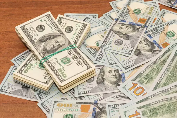 Ahşap masa arkaplan dokusunda yüzlerce dolarlık banknotlar. Bir tomar para ofis masasına saçıldı. zenginlik ve gelir kavramı