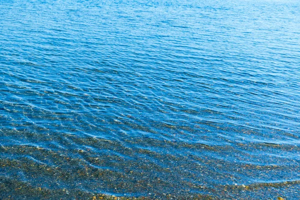Błękitna Powierzchnia Wody Morskiej Falami Pobliżu Brzegu Tekstura Tła — Zdjęcie stockowe