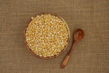 Çuval bezi dokusuna tahta kaşık ve kaşık ile işlenmemiş sarı tabak.