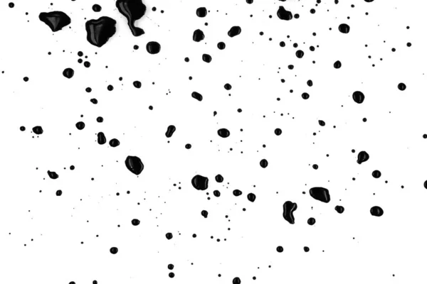 Drops of black paint splattered on a white background, texture