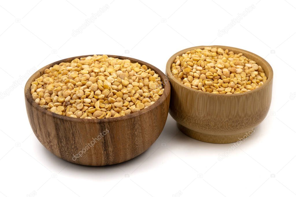 Raw yellow split peas in a wooden plate (bowl) isolated on white background
