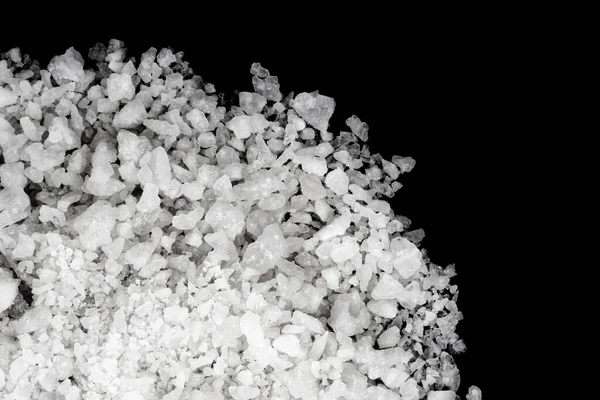 Spilled white sea salt isolated black background. Clear crystalline shaker pebbles on a black background, macro, close up