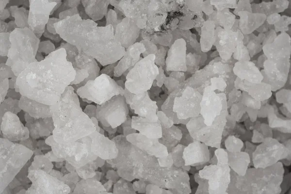 Spilled white sea salt texture background. Clear crystalline shaker pebbles macro, close up