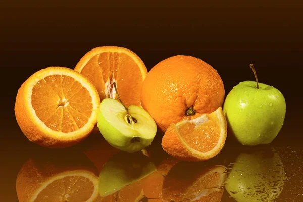 Apples and oranges fruits with drops and splashes of water on a black background