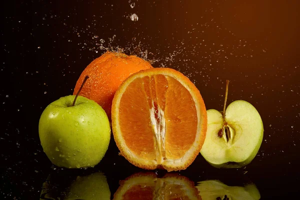 Apples and oranges fruits with drops and splashes of water on a black background