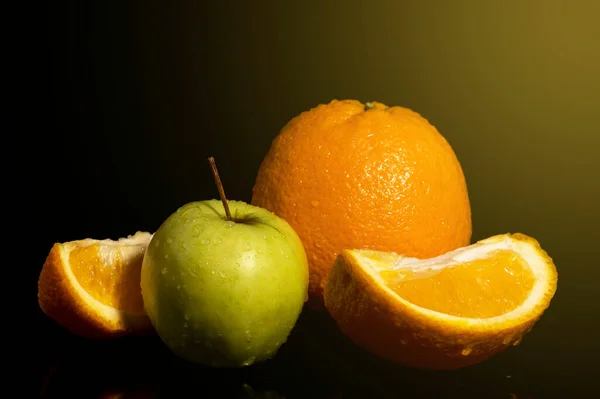 Apples and oranges fruits with drops and splashes of water on a black background