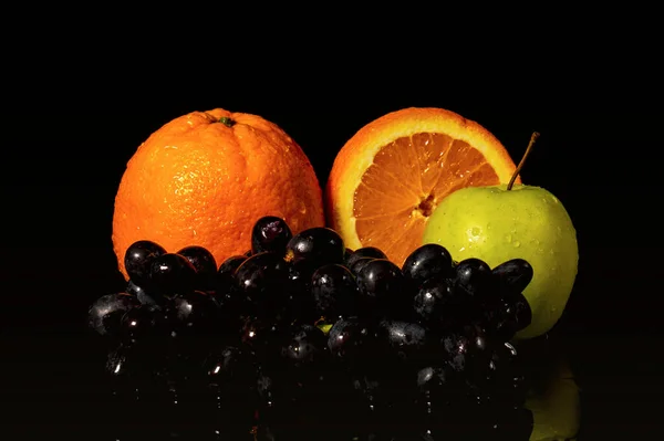 Apples and oranges fruits with drops and splashes of water on a black background