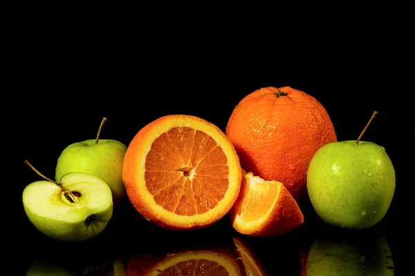 Apples and oranges fruits with drops and splashes of water on a black background