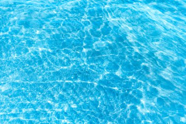  Sahilin arka planında mavi şeffaf deniz suyu. Güneşli bir günde hafif dalgalar ve parlayan temiz su yüzeyi. deniz tatili