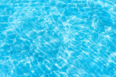  Sahilin arka planında mavi şeffaf deniz suyu. Güneşli bir günde hafif dalgalar ve parlayan temiz su yüzeyi. deniz tatili