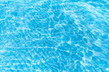  Sahilin arka planında mavi şeffaf deniz suyu. Güneşli bir günde hafif dalgalar ve parlayan temiz su yüzeyi. deniz tatili