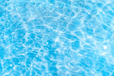  Sahilin arka planında mavi şeffaf deniz suyu. Güneşli bir günde hafif dalgalar ve parlayan temiz su yüzeyi. deniz tatili