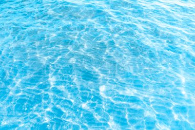  Sahilin arka planında mavi şeffaf deniz suyu. Güneşli bir günde hafif dalgalar ve parlayan temiz su yüzeyi. deniz tatili