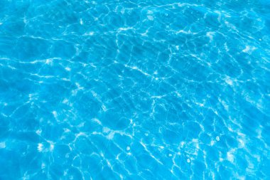  Sahilin arka planında mavi şeffaf deniz suyu. Güneşli bir günde hafif dalgalar ve parlayan temiz su yüzeyi. deniz tatili