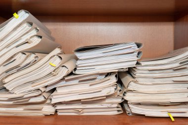 Arşivde birikmiş eski kağıt belgeler. Belgeler arşiv odasının raflarında. Ofis rafları dosyalarla dolu dolapta.