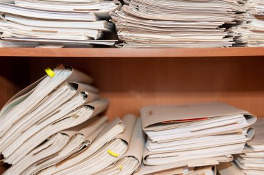 Arşivde birikmiş eski kağıt belgeler. Belgeler arşiv odasının raflarında. Ofis rafları dosyalarla dolu dolapta.