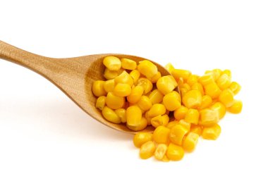 Beyaz arka planda izole edilmiş tahta kaşıkta mısır tohumları.