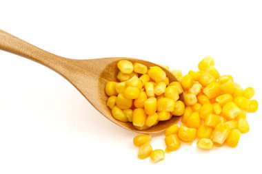 Beyaz arka planda izole edilmiş tahta kaşıkta mısır tohumları.