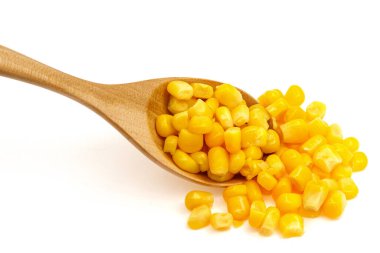 Beyaz arka planda izole edilmiş tahta kaşıkta mısır tohumları.