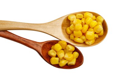 Beyaz arka planda izole edilmiş tahta kaşıkta mısır tohumları.
