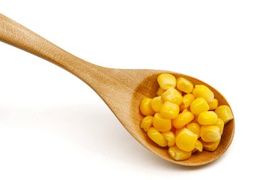 Beyaz arka planda izole edilmiş tahta kaşıkta mısır tohumları.
