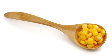 Beyaz arka planda izole edilmiş tahta kaşıkta mısır tohumları.