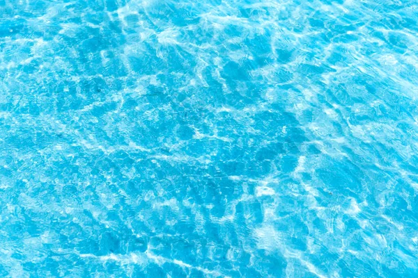  Sahilin arka planında mavi şeffaf deniz suyu. Güneşli bir günde hafif dalgalar ve parlayan temiz su yüzeyi. deniz tatili