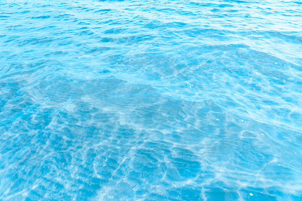  Blue transparent sea water near the beach texture background. clear water surface with slight waves and glare on a sunny day. sea vacation